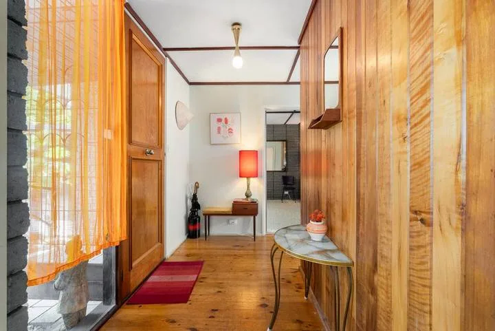 A narrow wood-paneled entryway with a small table and a glowing lamp.