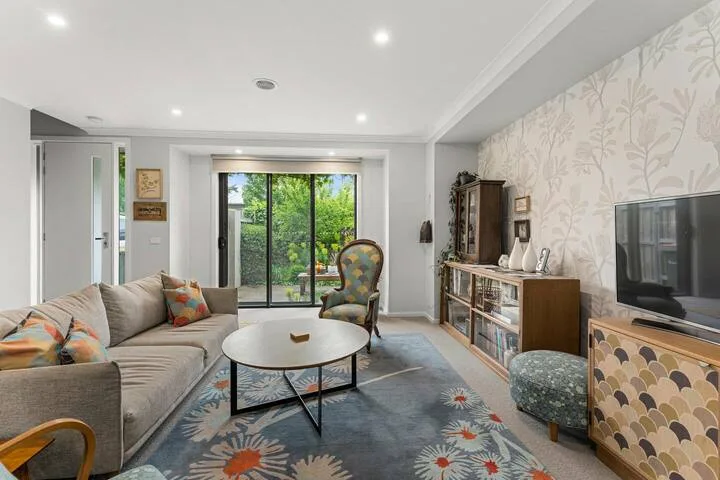 A bright living room with seating, a coffee table, and sliding glass doors.