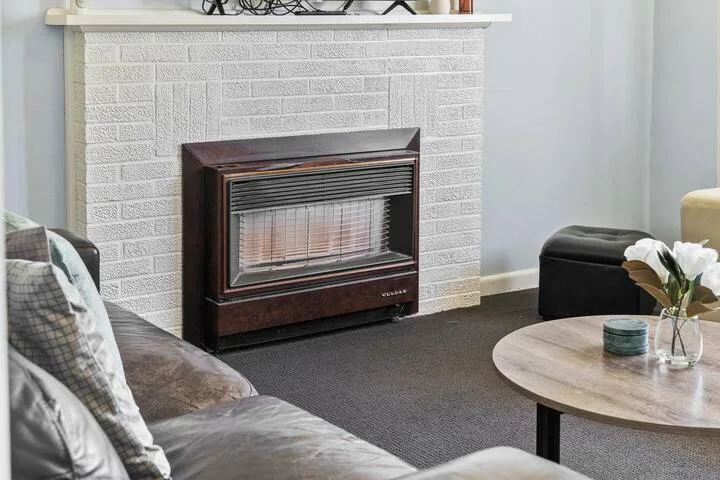A living room with a fireplace, seating, and a round coffee table.