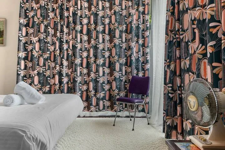 A bedroom with a bed, patterned curtains, and a chair.