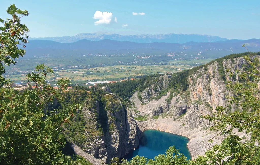 Un paisaje montañoso domina un desfiladero rocoso y una poza azul.