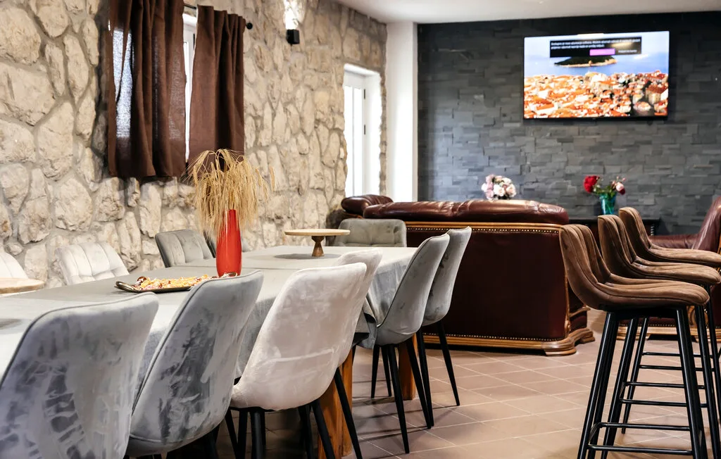 Una zona de estar y comedor con asientos, un televisor y una pared de textura pétrea.