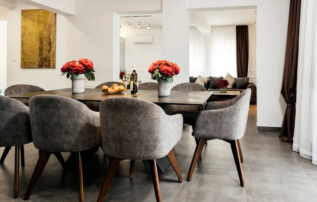 Comedor con una mesa oscura y asientos tapizados en gris.