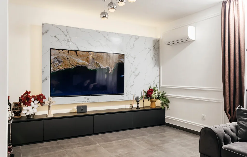 Una sala de estar con un televisor montado en la pared sobre un mueble oscuro y largo.