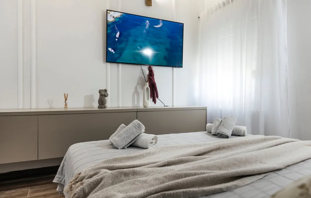 Un dormitorio con una cama bien tendida y un televisor sobre un mueble bajo.