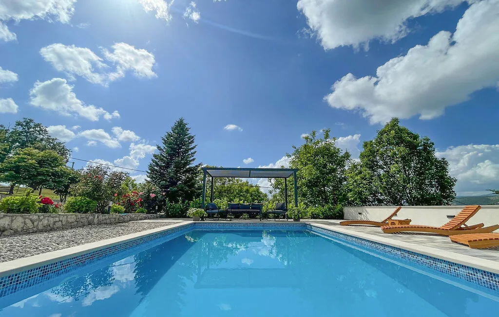 Una piscina al aire libre junto a tumbonas y una zona de estar con sombra.