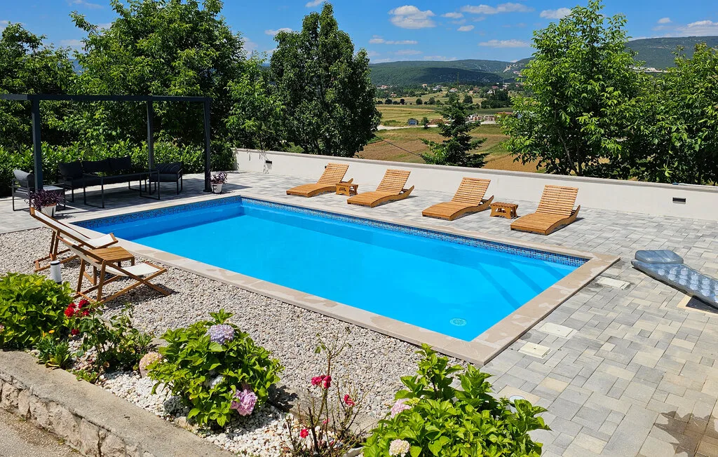Una piscina al aire libre con tumbonas tiene vistas a un valle verde.