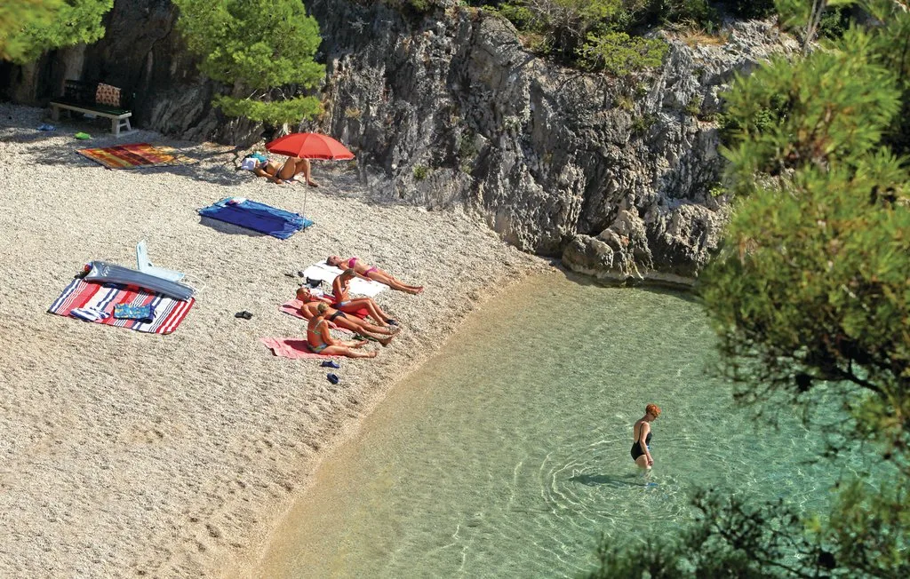 Una pequeña cala con personas descansando en la arena y nadando en aguas claras.