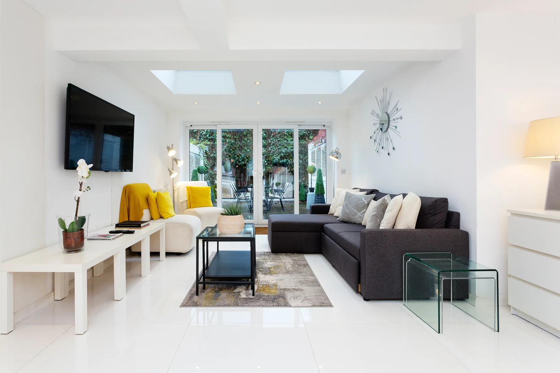 Una sala de estar luminosa con un sofá seccional oscuro y una mesa de centro de vidrio.