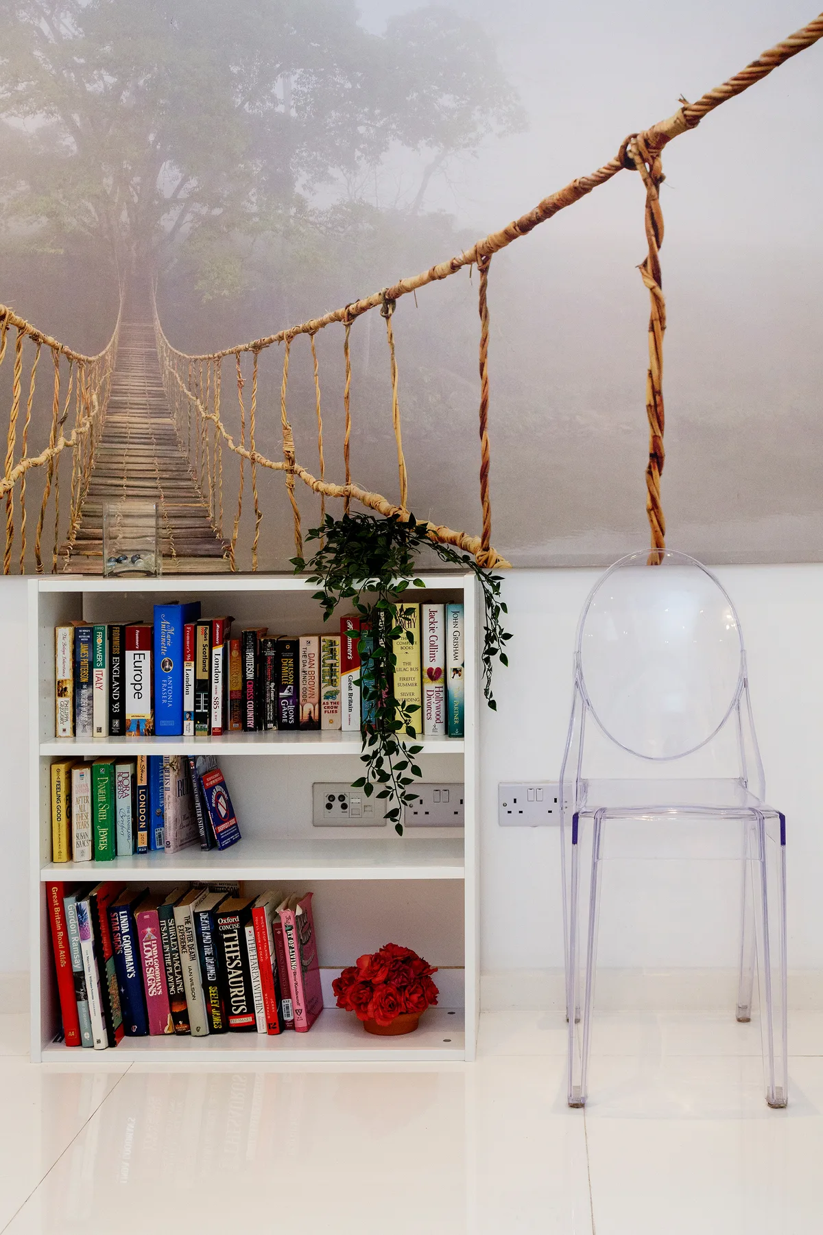 Una luminosa zona de lectura tiene una estantería llena de libros y una silla transparente.