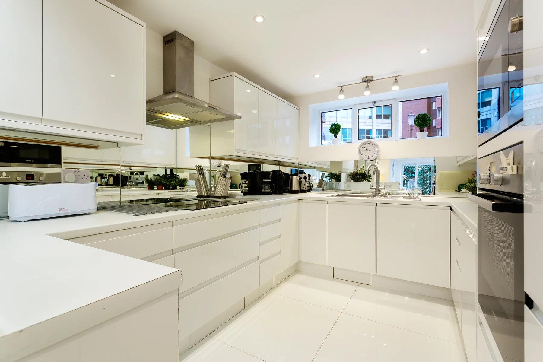 Una cocina moderna y luminosa con gabinetes blancos y una larga encimera.