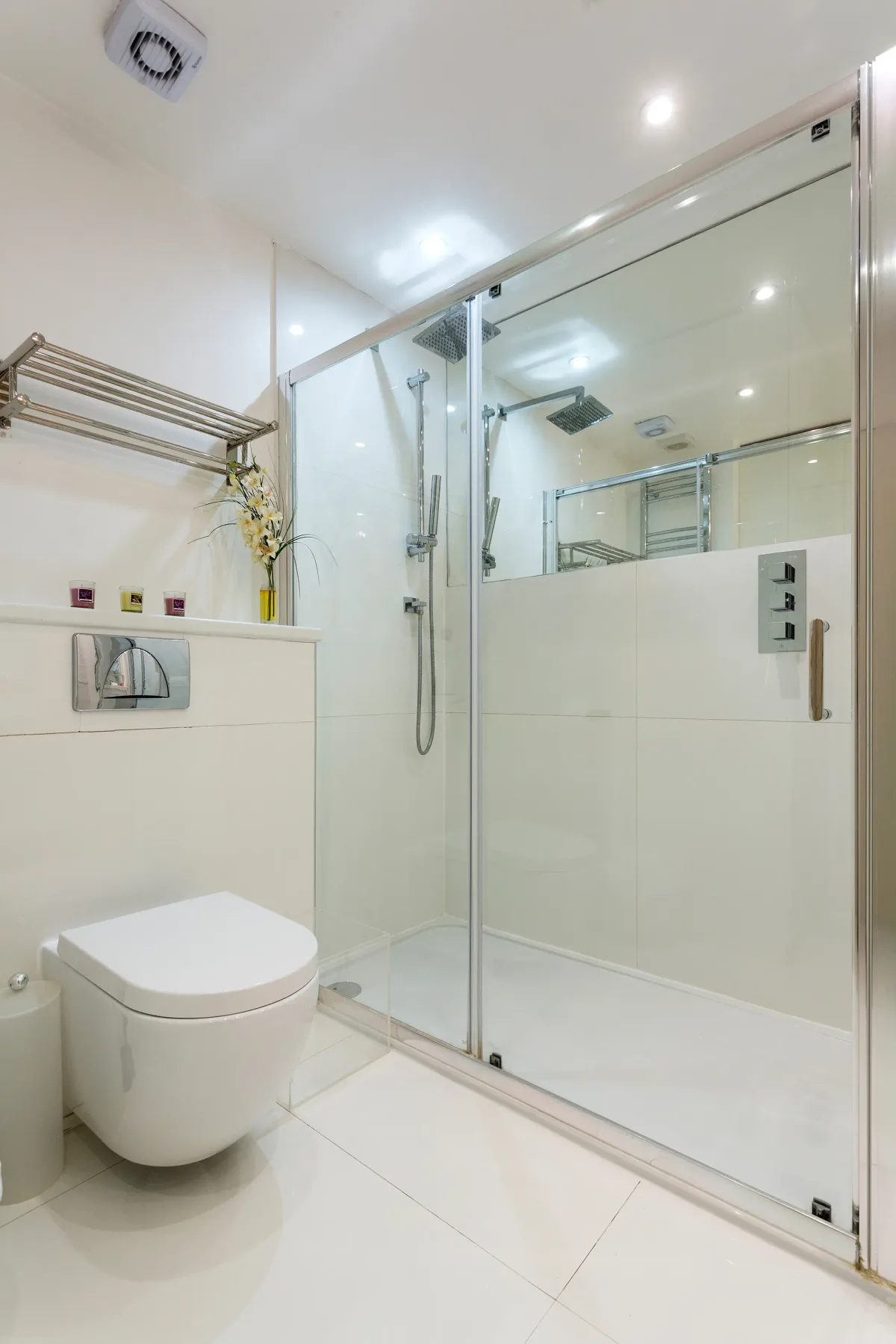 Un baño luminoso con inodoro y ducha con mampara de vidrio.