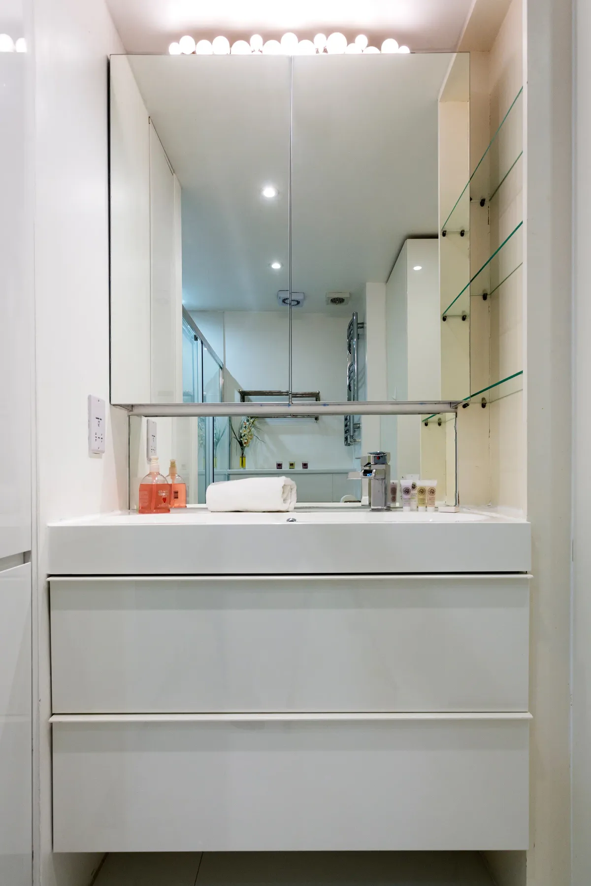 Un tocador de baño luminoso con un espejo grande y un lavabo sobre la encimera.