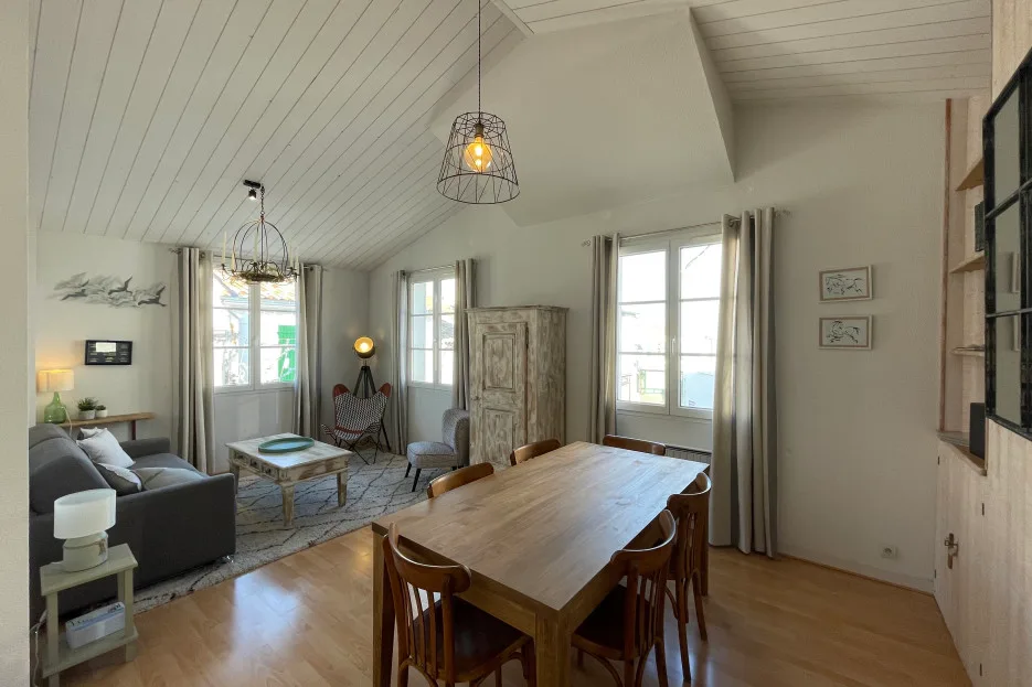 A bright living and dining room with a long wooden table and seating.