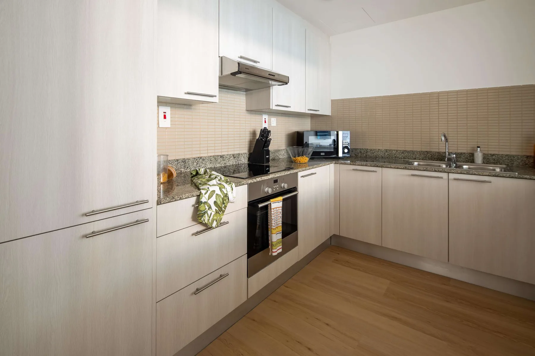 Una cocina moderna con armarios claros, encimeras oscuras y un horno integrado.
