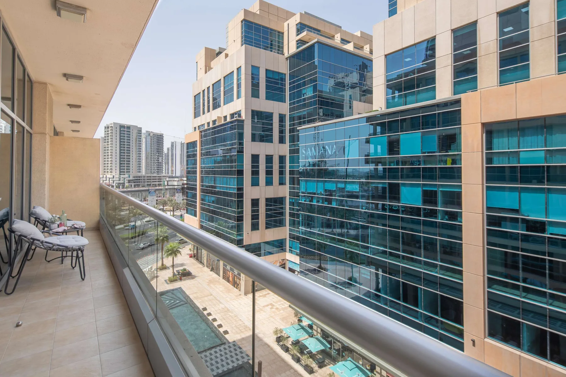 Un balcón da a modernos edificios de oficinas con fachadas de vidrio y un patio ajardinado.