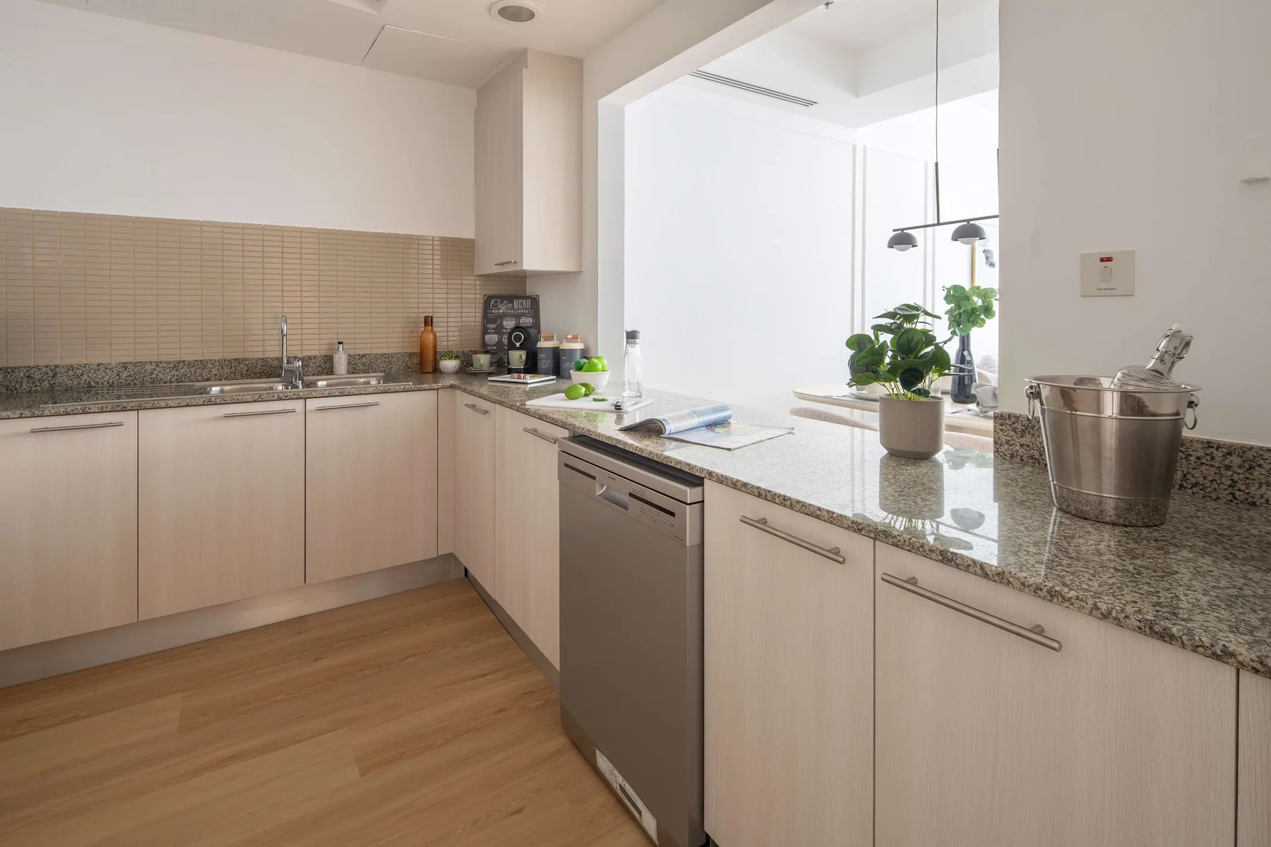 Una cocina luminosa con gabinetes claros y una encimera de piedra.
