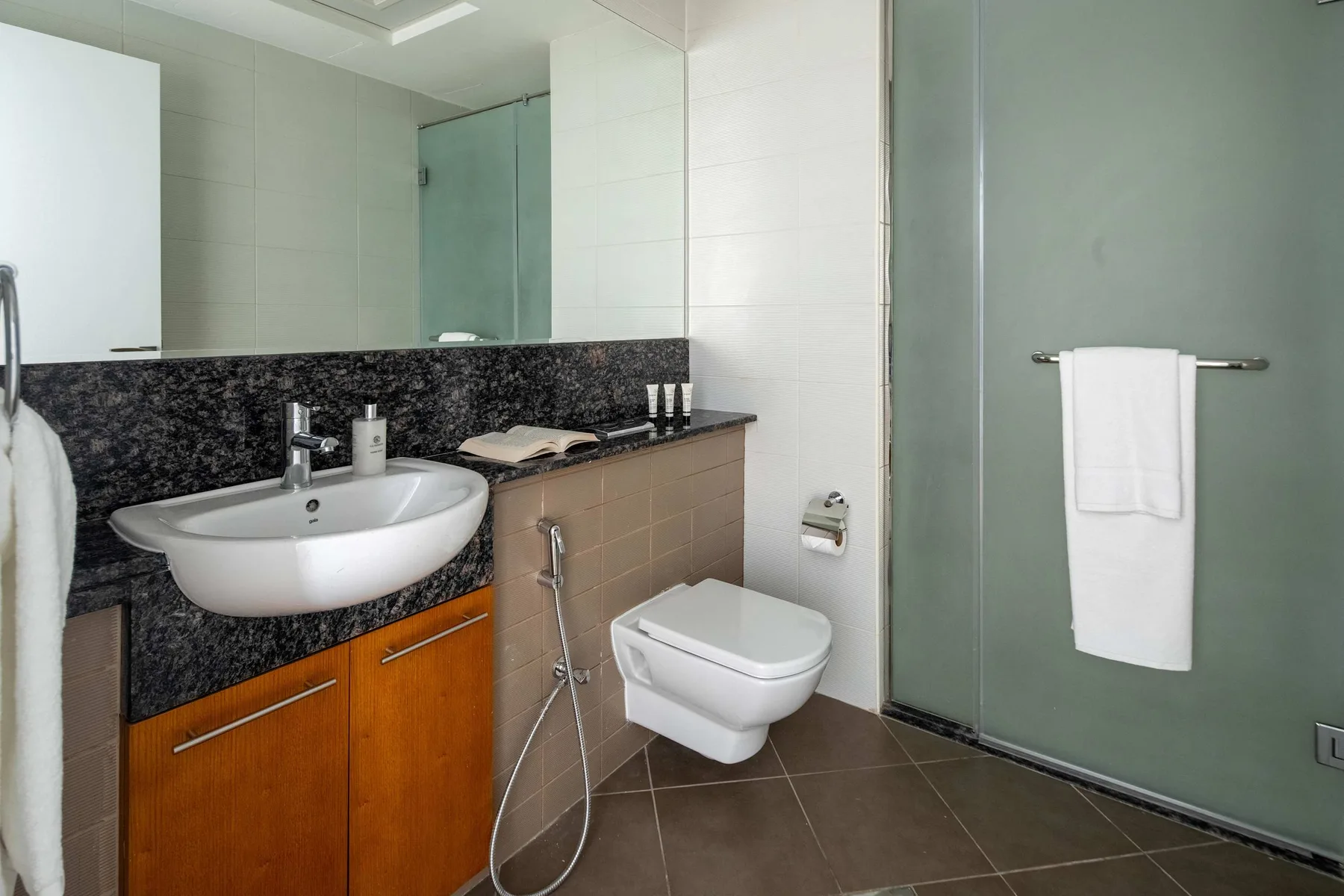 Un baño con azulejos, lavabo, inodoro y panel de ducha de vidrio.