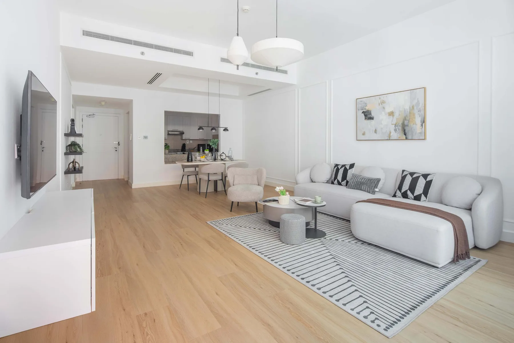 Una sala luminosa con zona de estar, mesa de centro y espacio de comedor.
