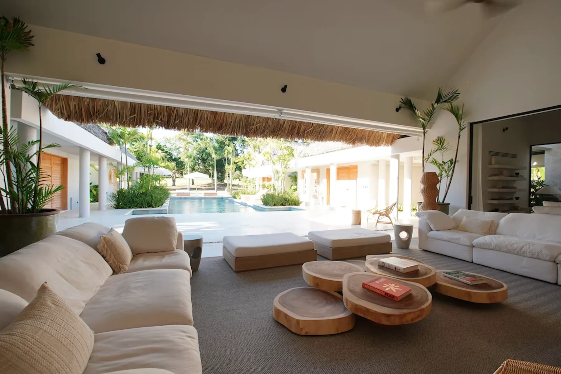 An open-air lounge with low seating and a pool visible beyond.