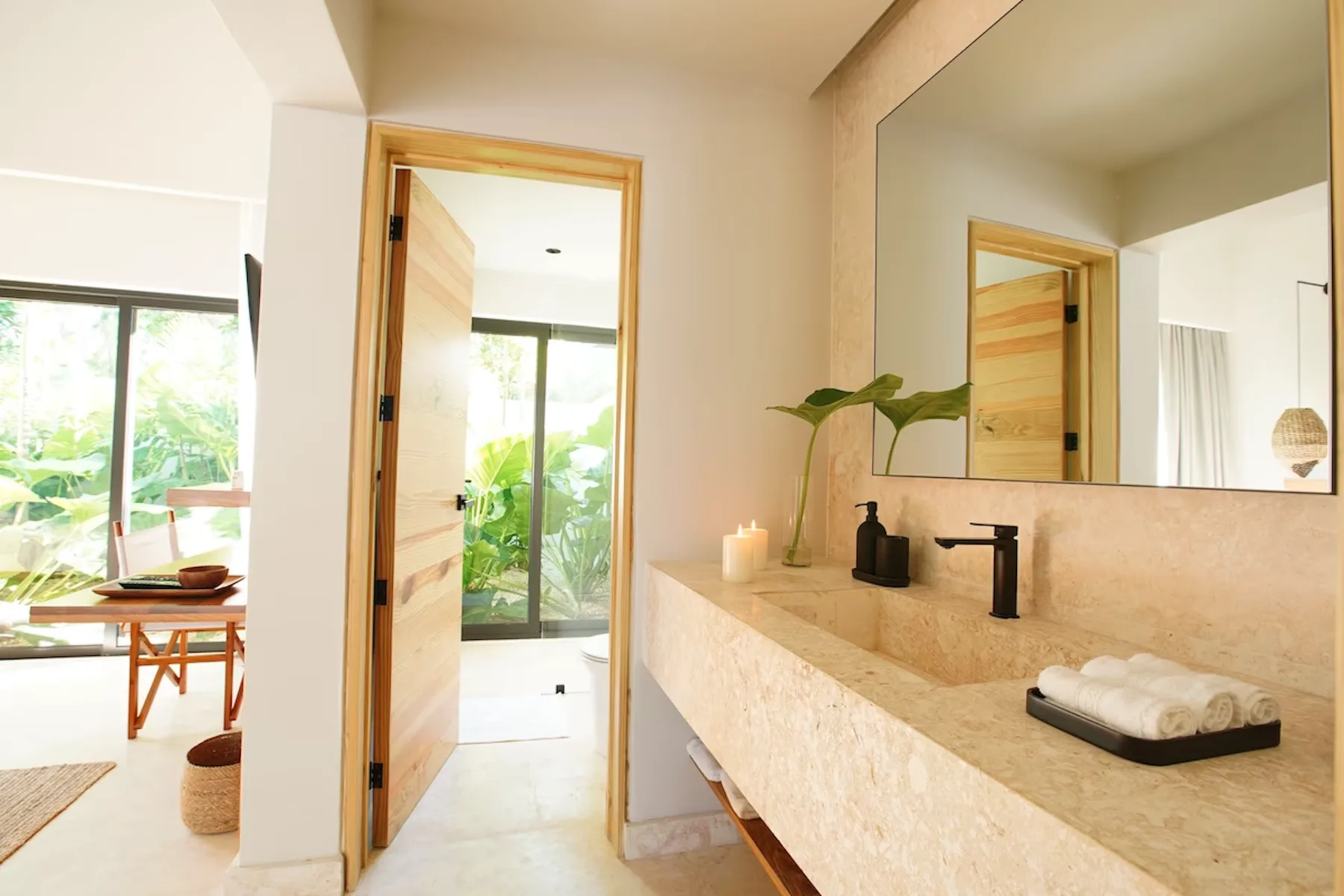 A bright bathroom with a stone vanity and a large mirror.