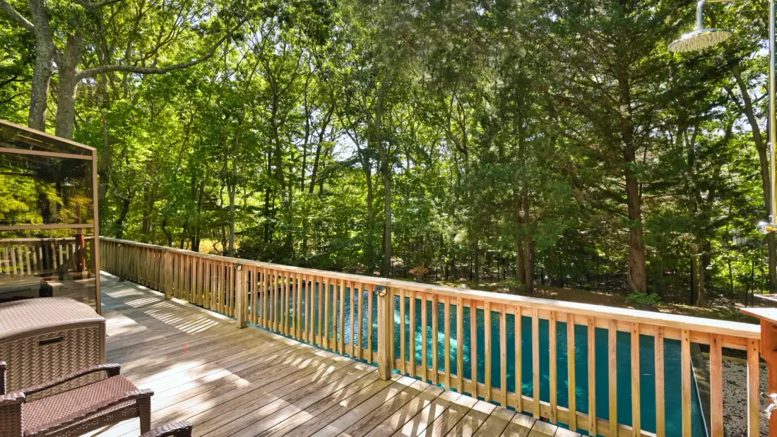 A wooden deck overlooks a tree-lined body of water.