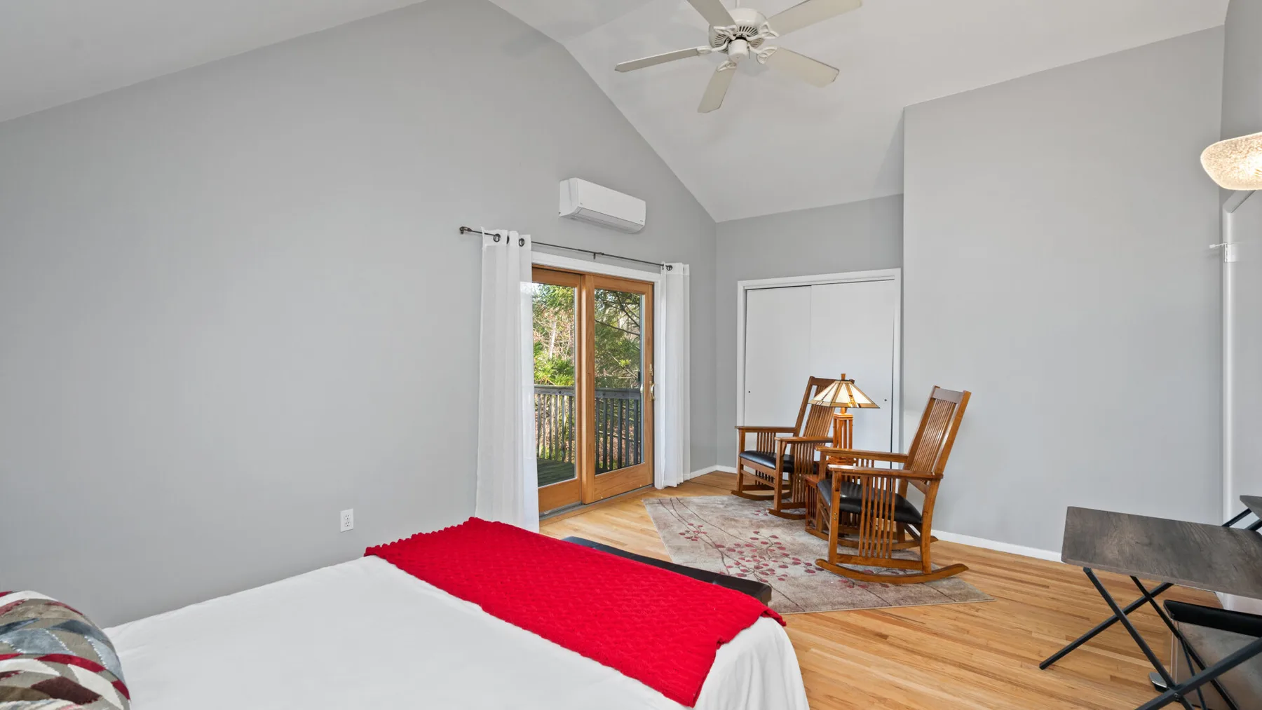 A bedroom with a bed, dining table, and seating by the windows.