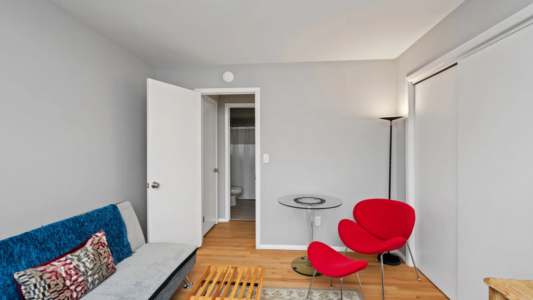 A living room with a blue-covered seating area and a red accent chair.