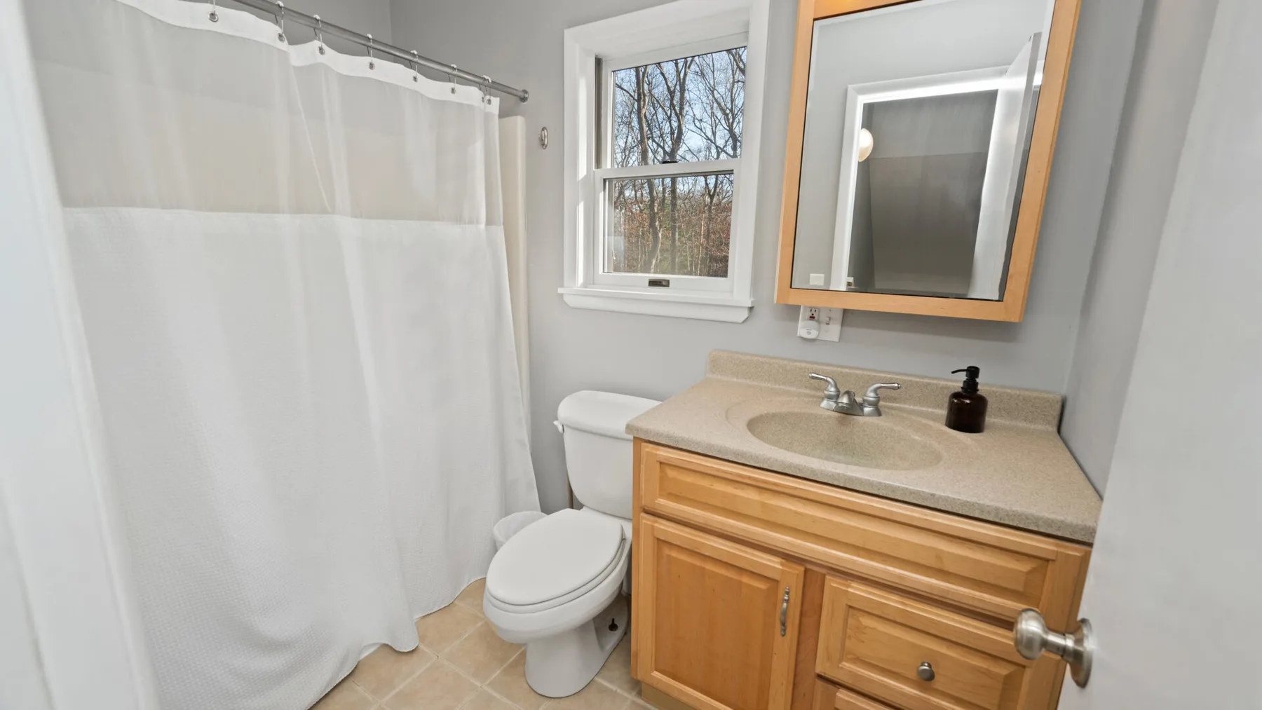 A bathroom with a vanity, toilet, and white shower curtain.