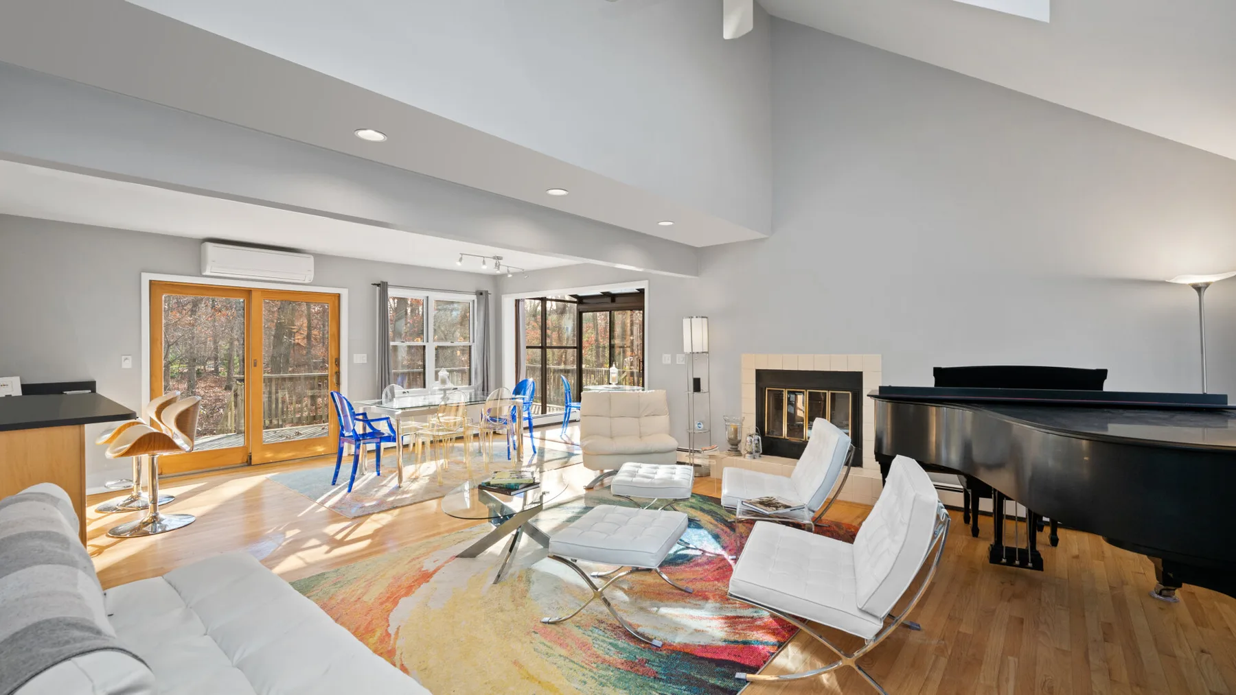 A bright open-plan living and dining area with seating, a table, and a fireplace.