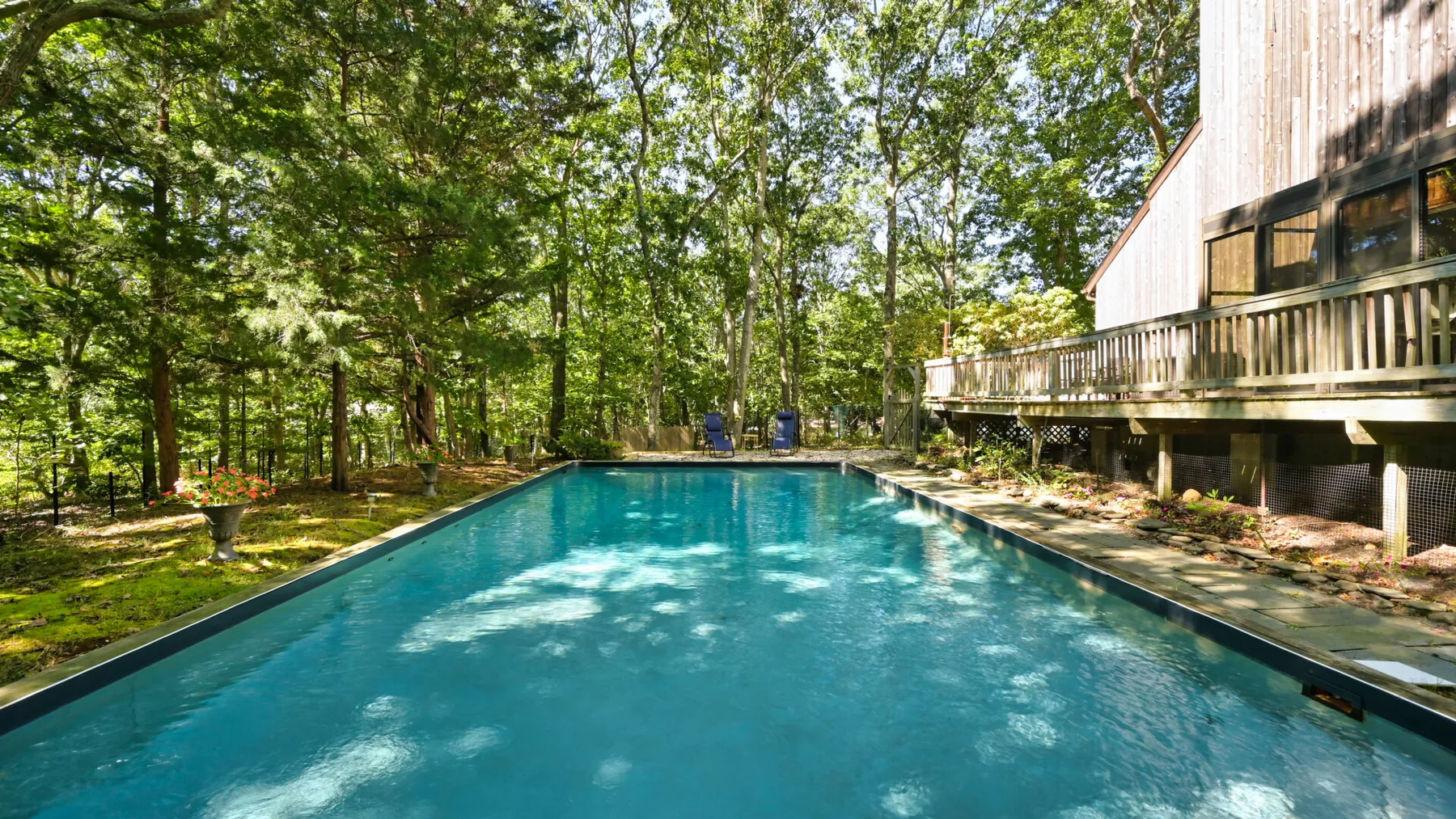 An outdoor swimming pool beside a wooded property.
