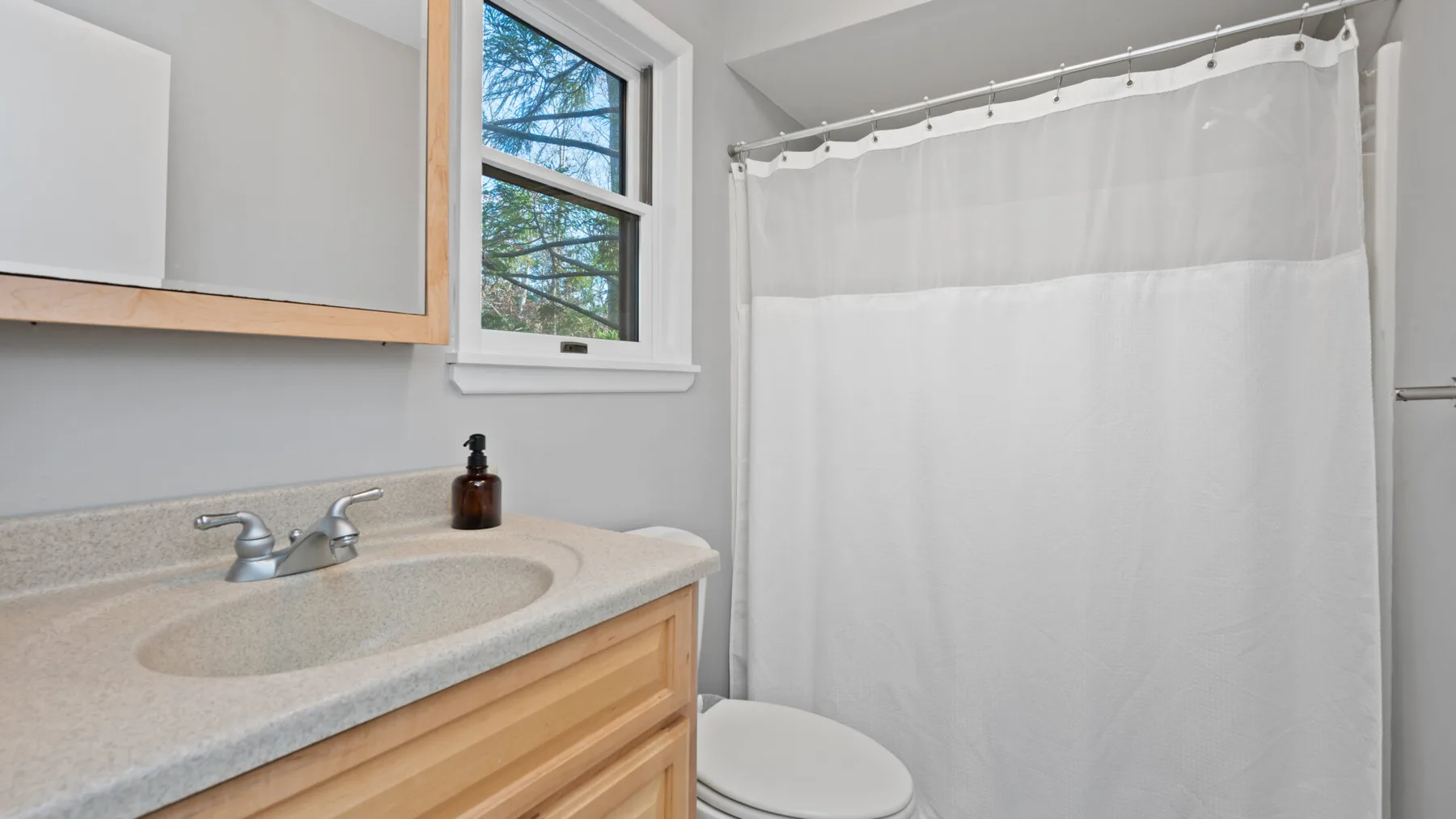 A bathroom vanity and sink sit beside a curtained shower.