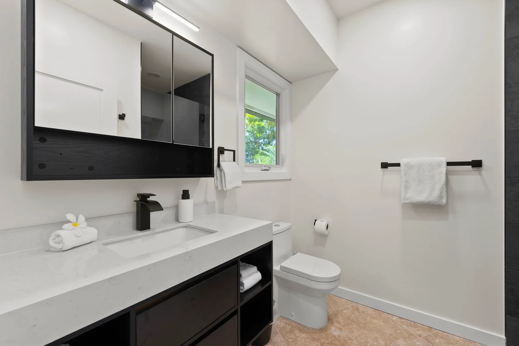 Un baño luminoso con tocador, espejo e inodoro.