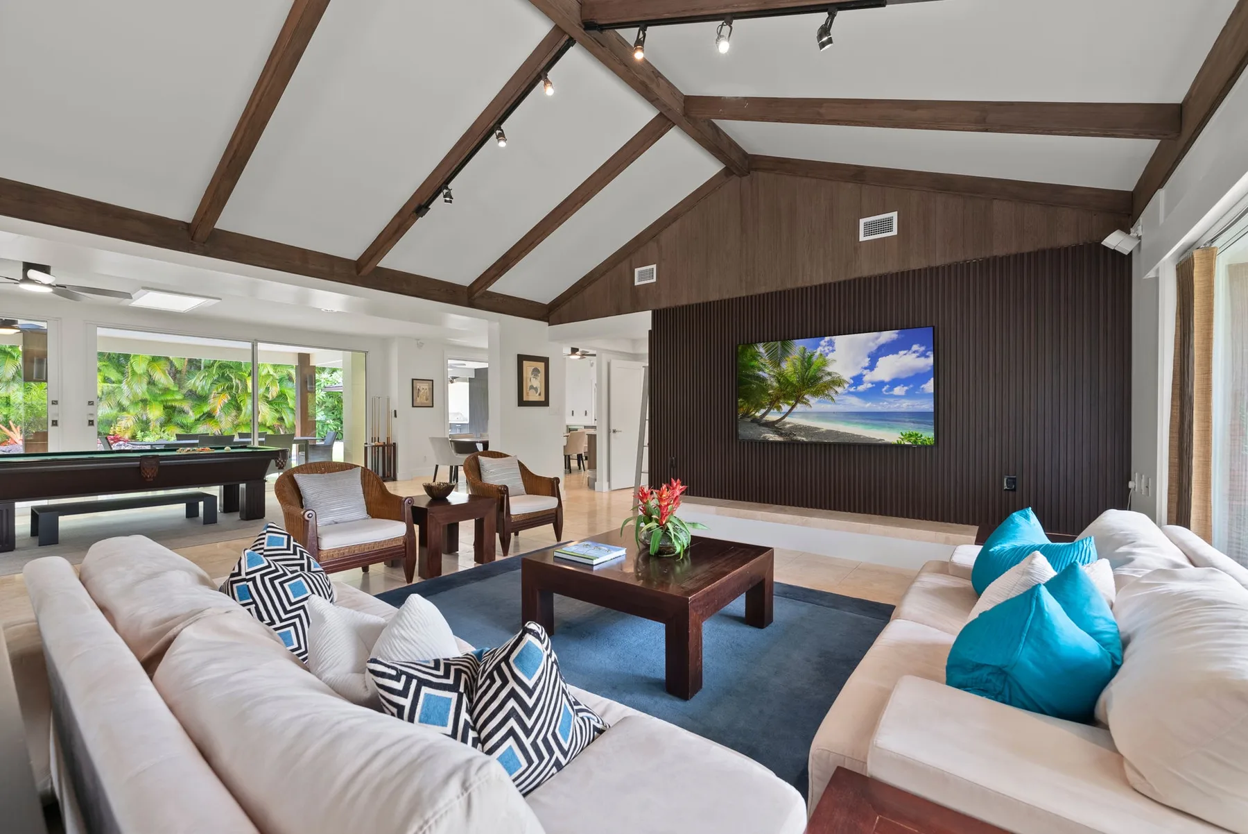 A spacious living room with seating arranged around a coffee table and television.