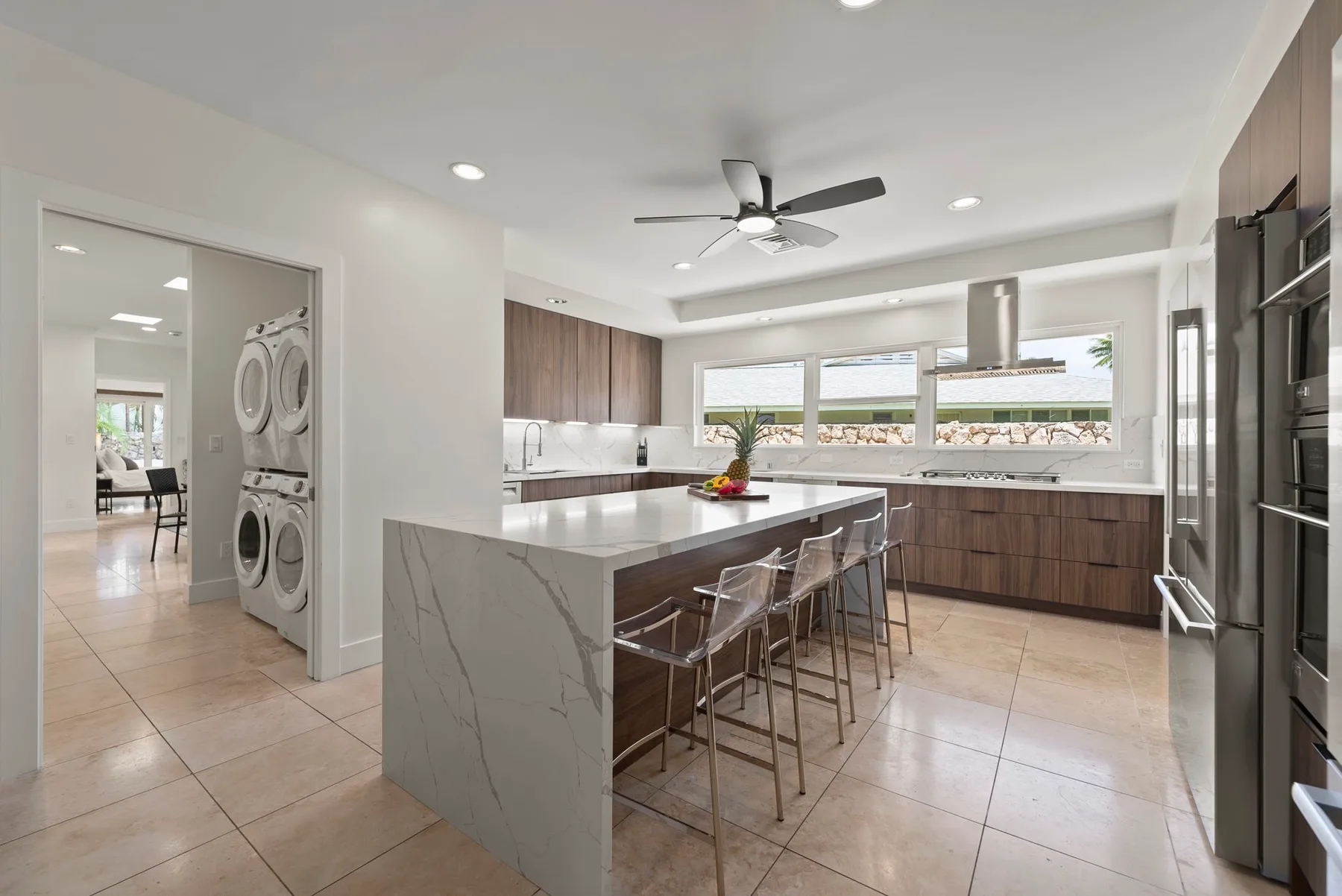 Una cocina luminosa con isla central, asientos de barra y ventanas amplias.