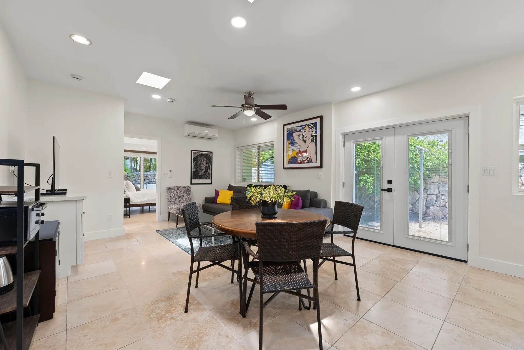 Una luminosa zona de comedor y sala de estar con mesa, asientos y puertas de vidrio.