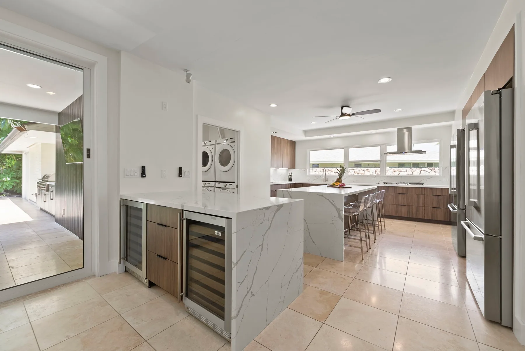 Una cocina luminosa con isla central, asientos de barra y electrodomésticos de acero inoxidable.