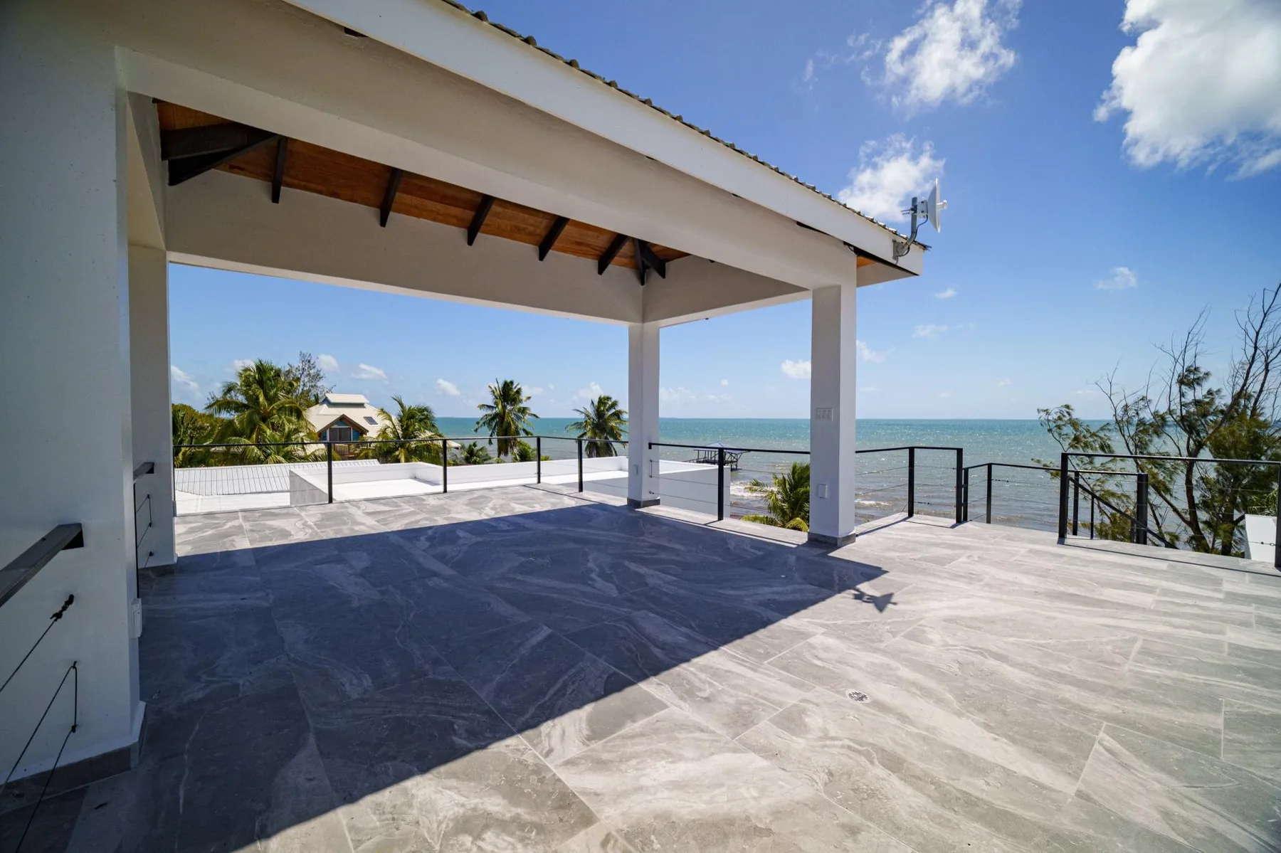 A covered terrace overlooks the sea, with tiled flooring and open sides.