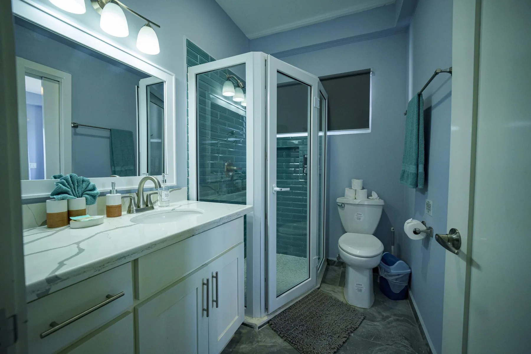 A bathroom with a vanity, glass shower, and toilet.