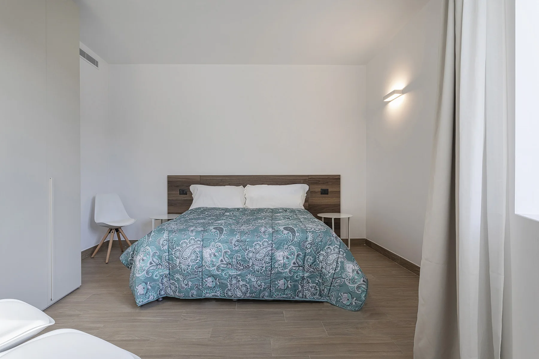 Un dormitorio con una cama cubierta con una colcha estampada de color turquesa.
