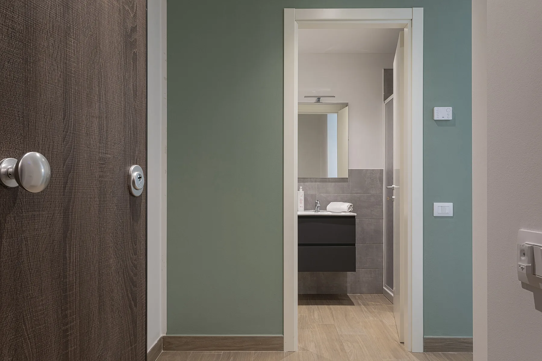 Una puerta da a un baño con lavabo y espejo.