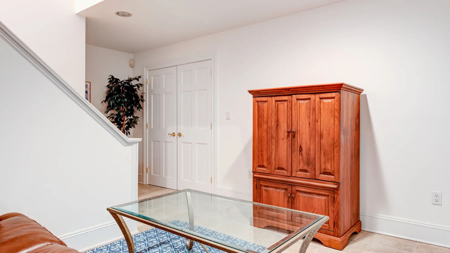 A bright interior landing features a glass coffee table and a wooden cabinet.