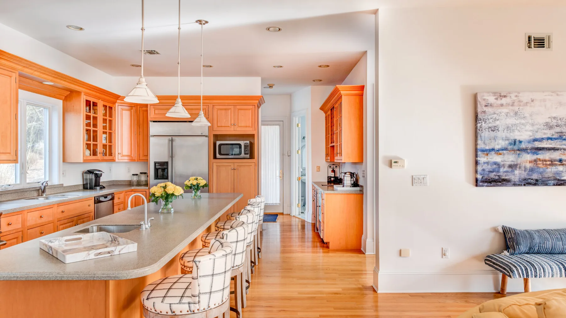 A bright kitchen with orange cabinetry, a large island, and seating.