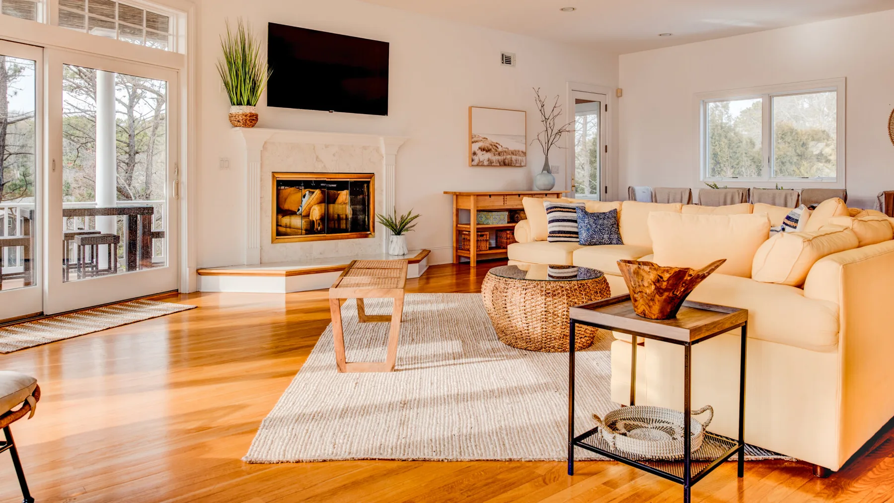 A bright living room with a fireplace, seating, and large windows.