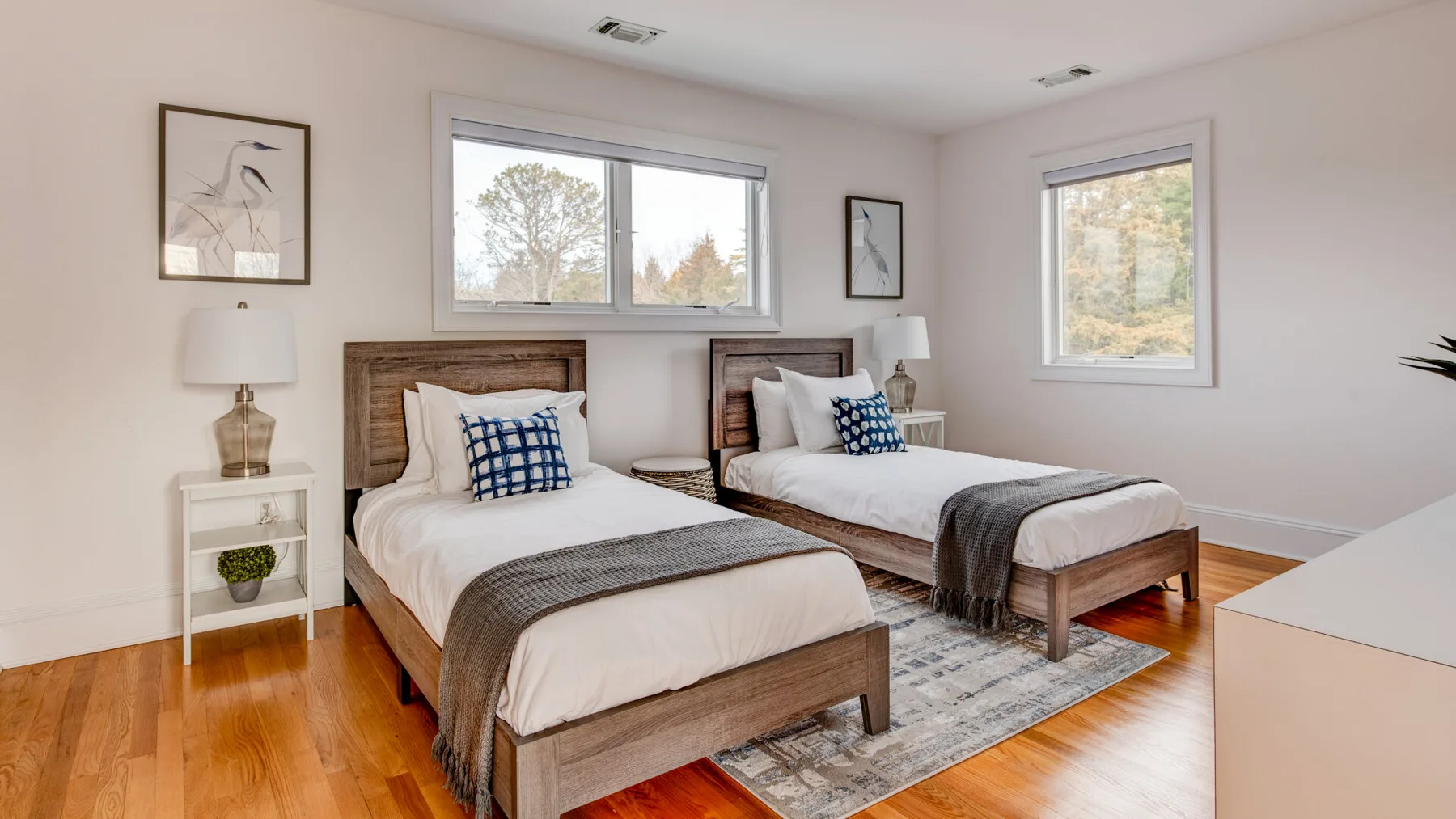 A bright bedroom with two beds and large windows.