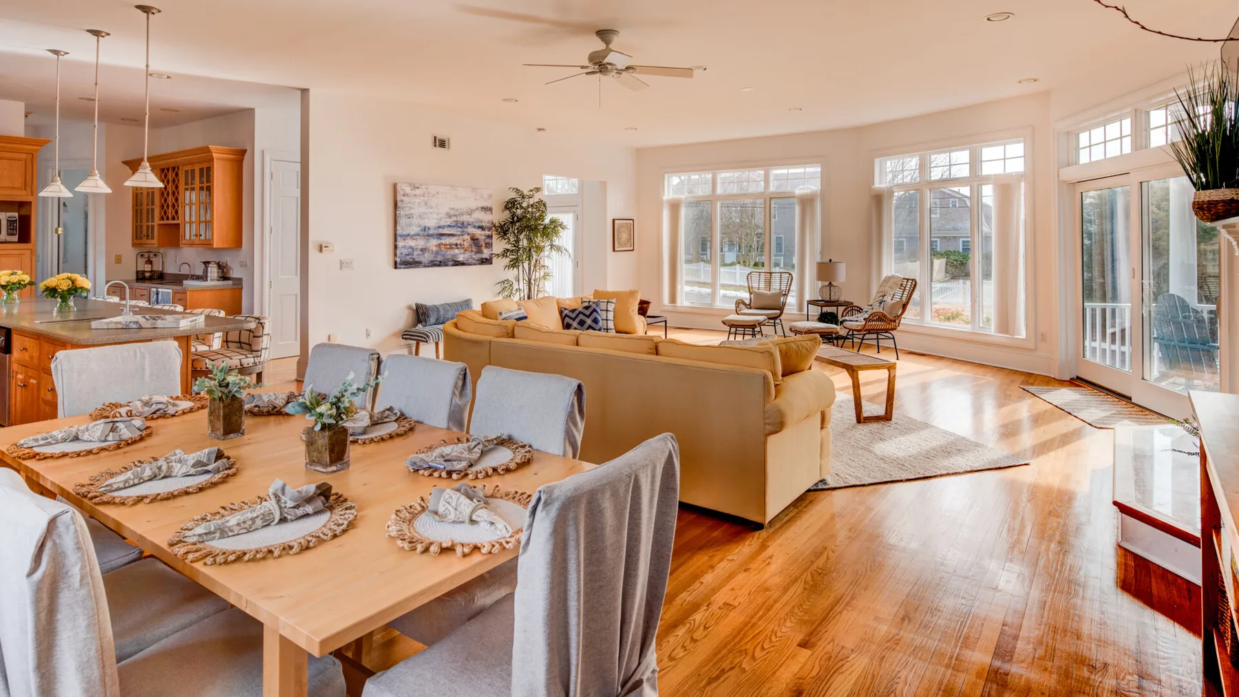 A bright open-plan living and dining area with large windows and a table set for dining.