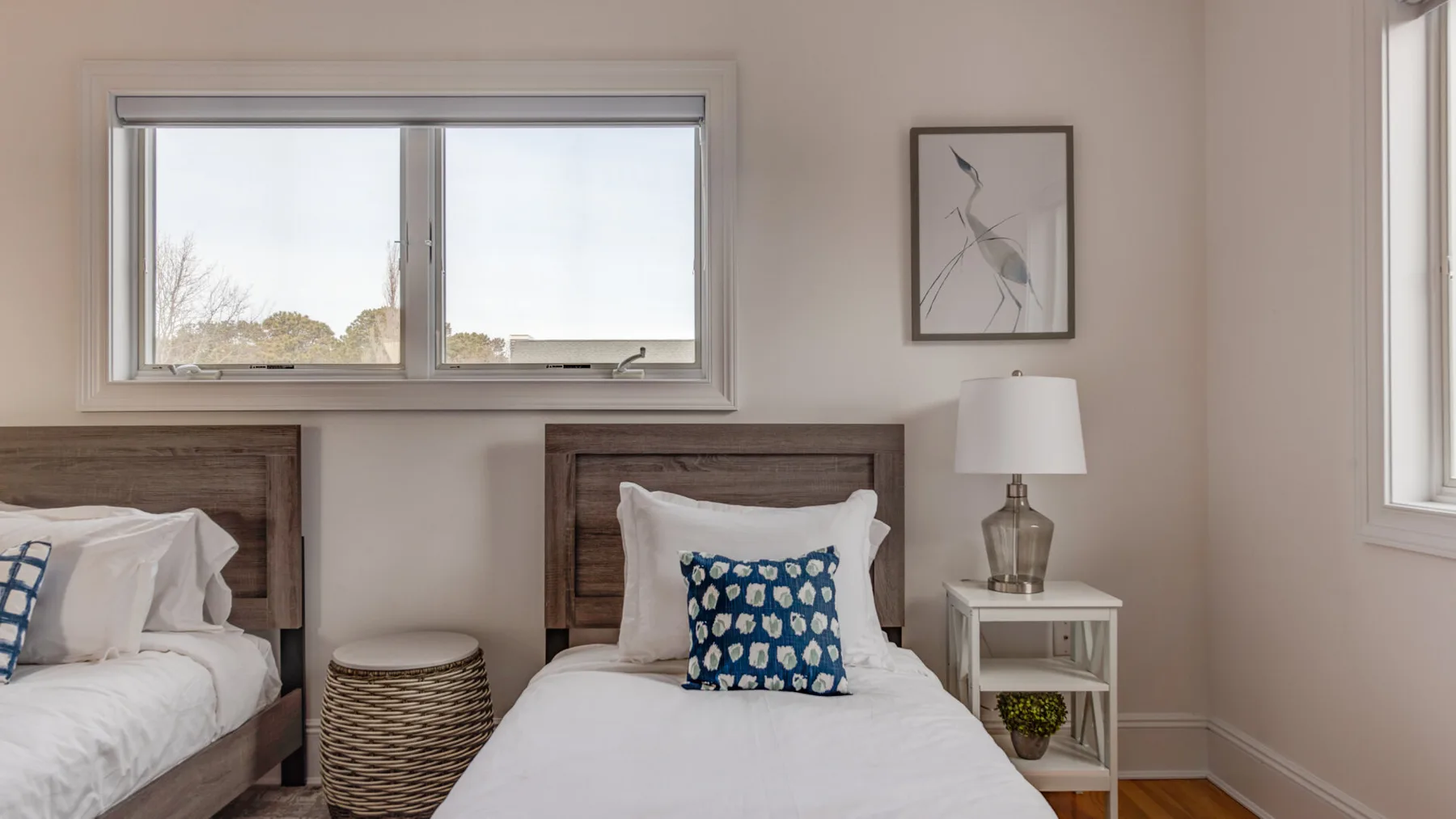A bedroom with two beds, blue patterned pillows, and windows.