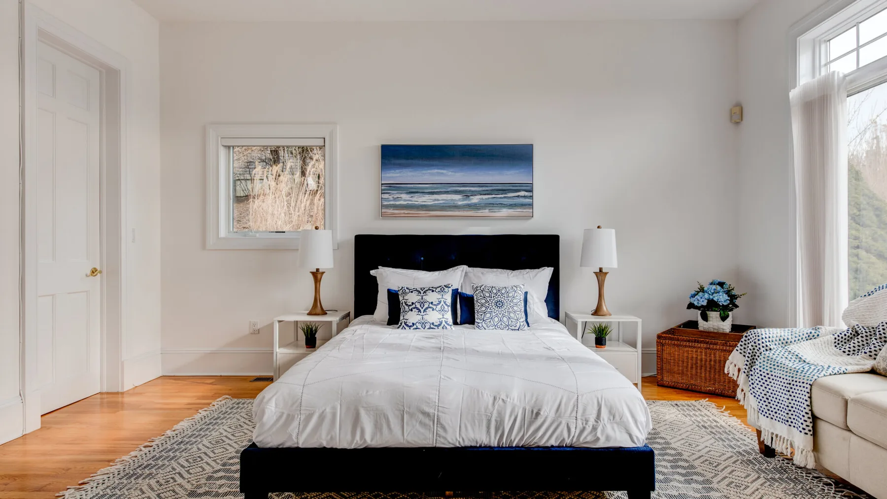 A bright bedroom with a neatly made bed and a large window.