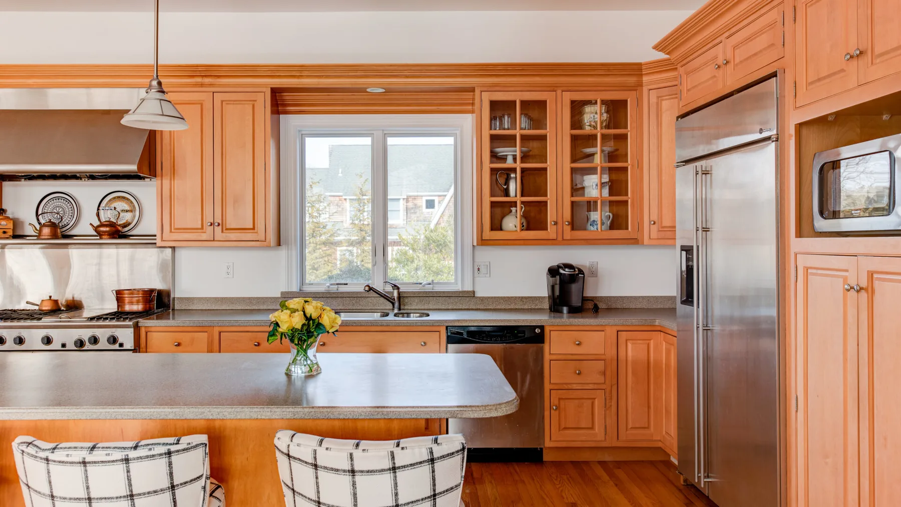 Una cocina de tonos cálidos con gabinetes de madera, una isla central y una ventana.