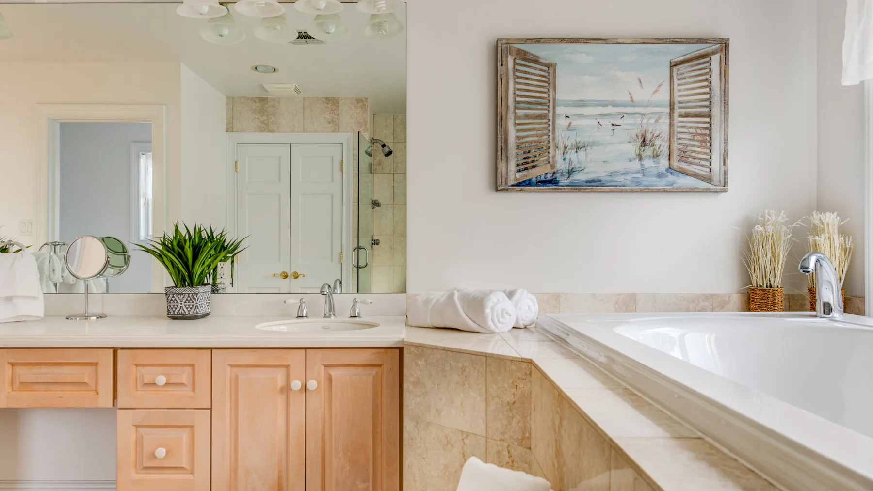 A bright bathroom with a vanity, sink, and bathtub beneath framed wall art.